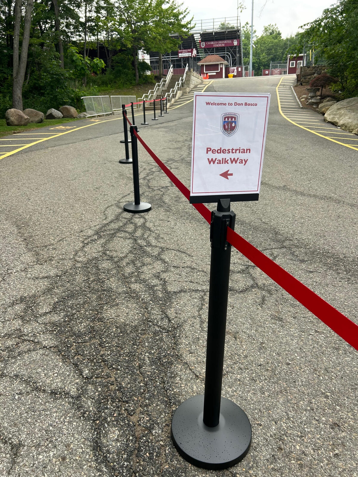 Long outdoor stanchion queue line with signage at Don Bosco school event