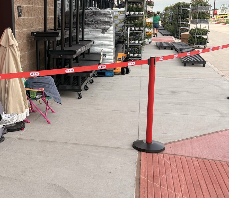 Red retractable belt stanchion forming an outdoor queue at an H-E-B store